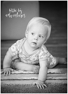 A baby of about 1yrs old looks out her childcare room door at the big world.  Little Big Adventures captured the moment