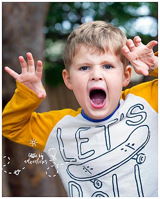 A boy roars like a lion at his kindergarten.  His hands mimic a lions fierce paws.  Photo by Little Big Adventures photography.