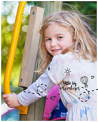 kindergarten aged girl climbing into a fort at her kindy and looking back at the camera